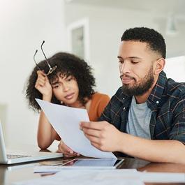 Couple reviews documents by laptop