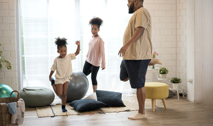 Father and his two daughters stretching at home.