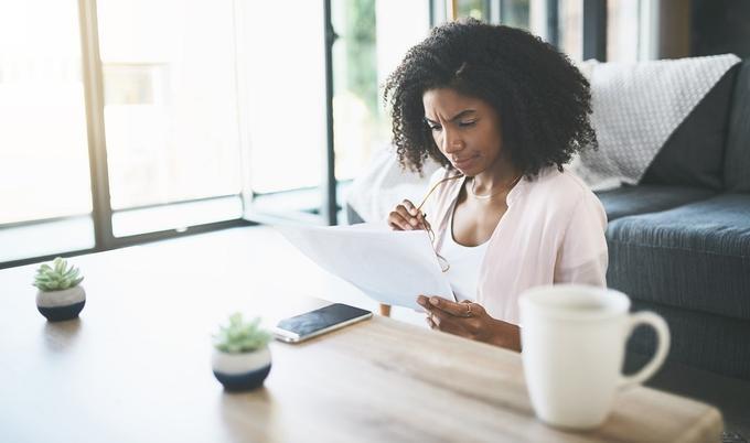 Woman sitting on floor while reading paperwork.