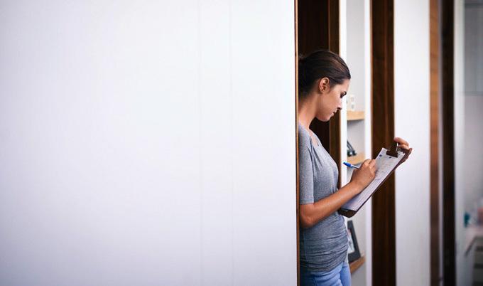 Woman writing on clipboard in doorway.