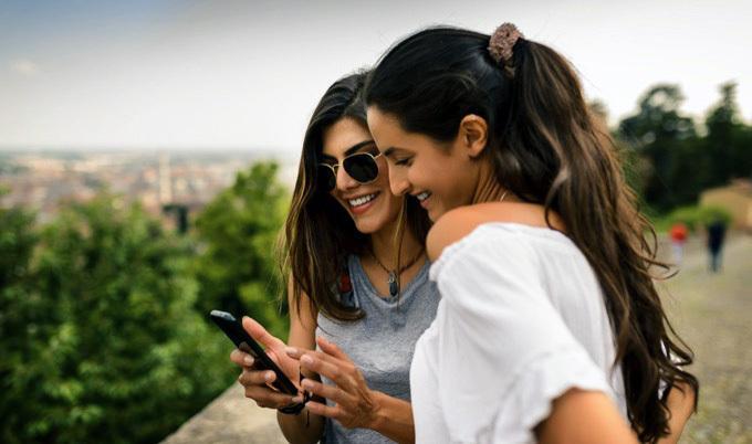 Two young women looking at something on a mobile phone together.