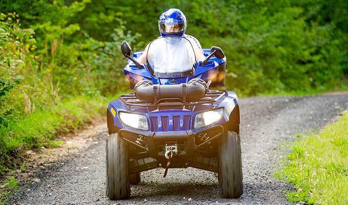 man on blue atv dirt road