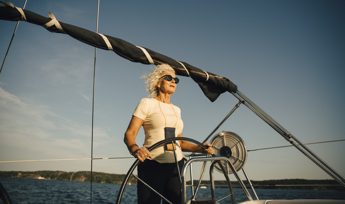 Woman driving a sail boat on a body of water.