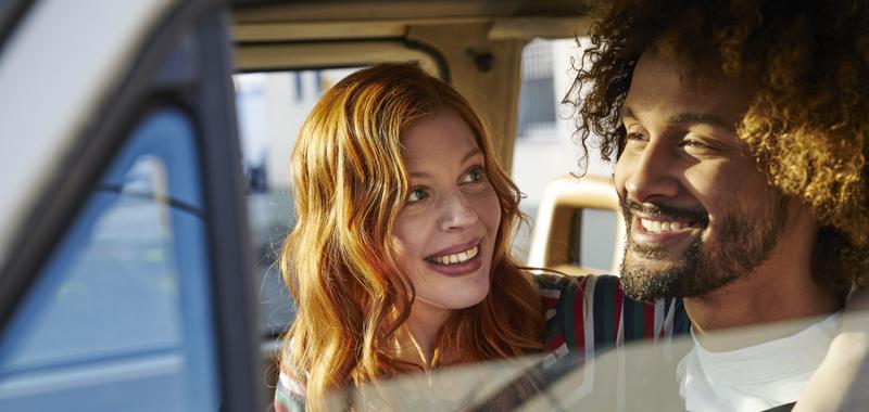 woman with arm around man driving in car