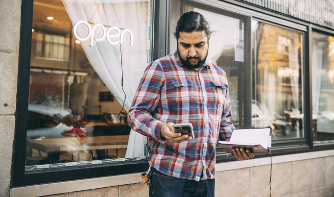 Man looking at phone outside of restaurant