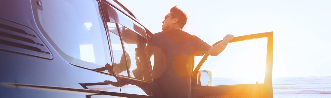 Enjoying sunset at beach hanging onto car