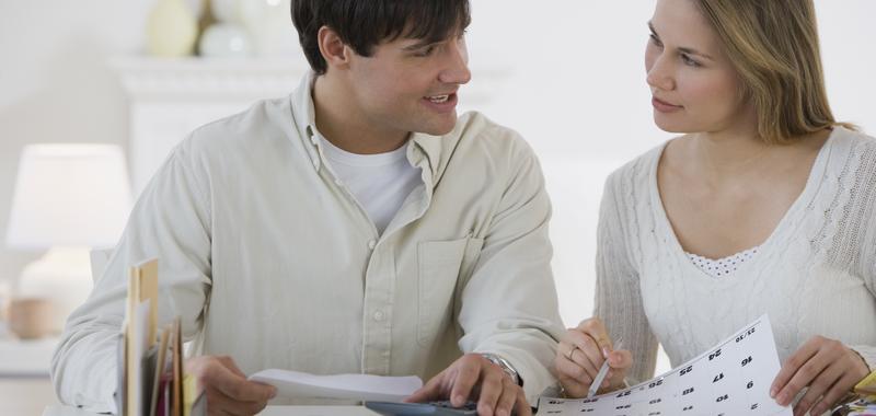 couple looking at one another discussing documents in front of them 