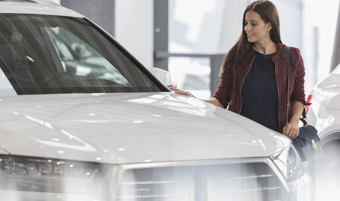 A woman is at a dealership shopping for a new car.