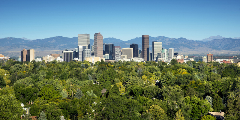 The towering high rises of Denver's downtown sit between the Front Range of the Rocky Mountains to the west and the tree lined neighborhoods and parks of the city to the east.