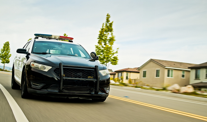 Police car driving down neighborhood street.