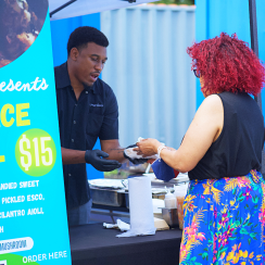 Patrick D. Tyler II serving food to a woman at his vendor booth.