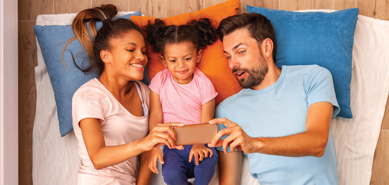 family laying down looking at cell phone 