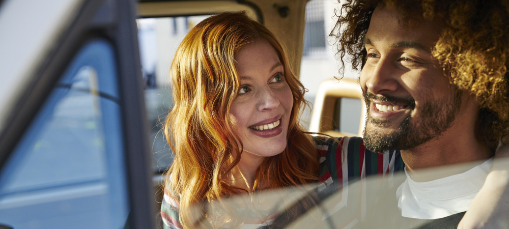 woman with arm around man driving in car