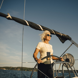 Woman driving a sail boat on a body of water.