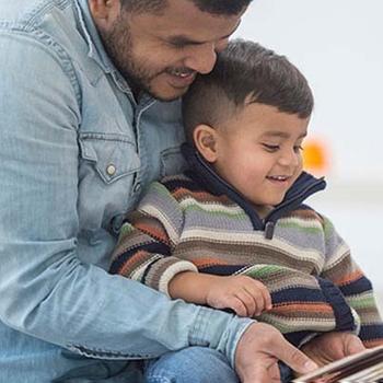Dad reading book with son.