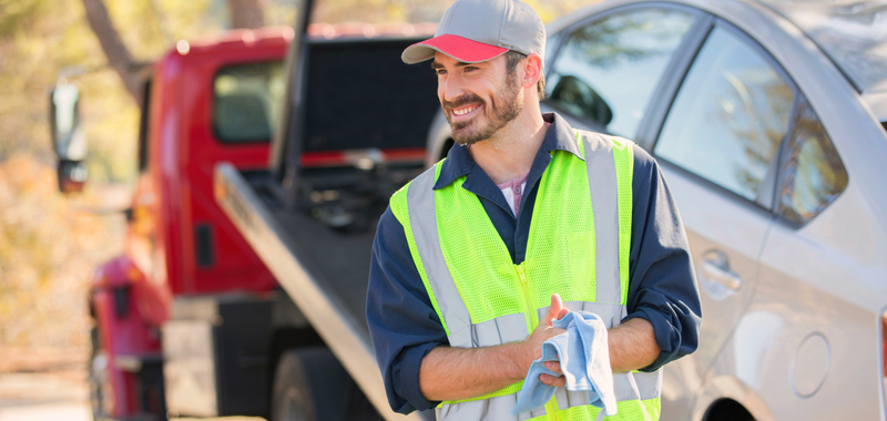 man standing in front of roadside assistance tow truck