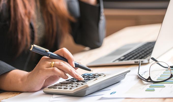Woman with pen in hand using a calculator.