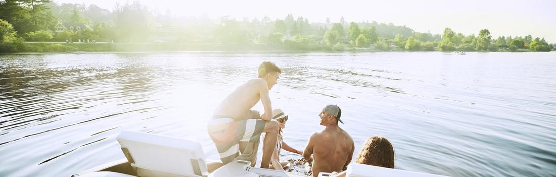Smiling family hanging out on swim deck of boat on lake on summer afternoon