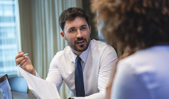 Man sitting at a table discussing paperwork with a woman.