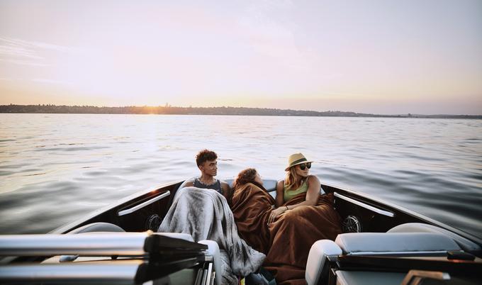 Mother and children riding in bow of boat on summer evening
