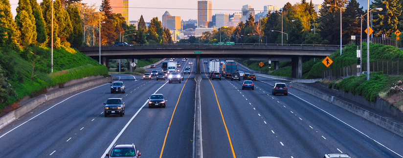 Aerial shot of a six-lane highway with cars and trucks driving in both directions.