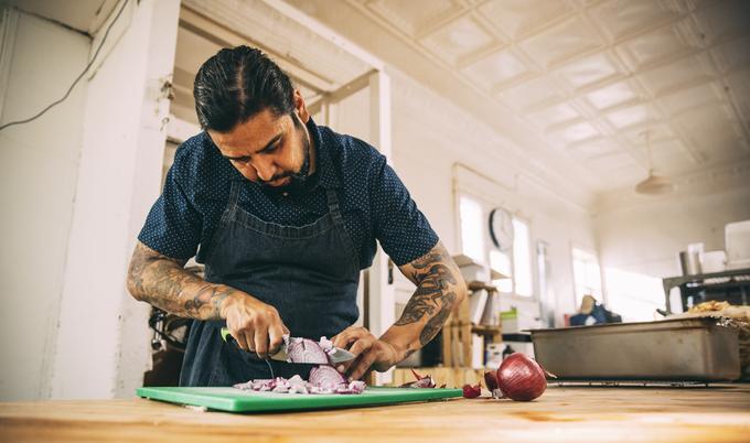 Man chopping onions in restaurant kitchen