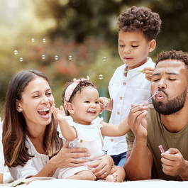 Parents and grandparents blowing bubbles with two small children
