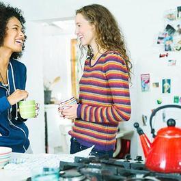 two women laugh in kitchen