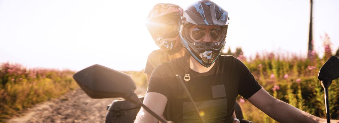 Man driving ATV&nbsp;with girlfriend sitting behind and enjoying the ride in nature.