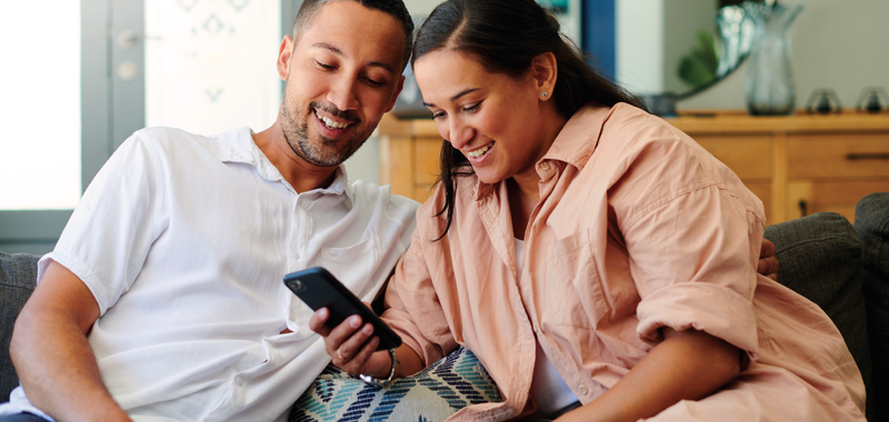couple smiling and looking at mobile phone