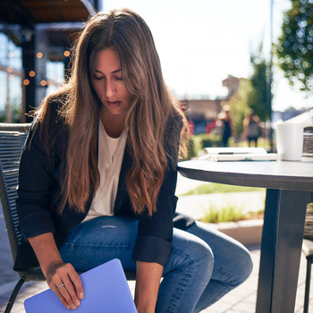 Woman sitting at a table putting a file away in a briefcase.