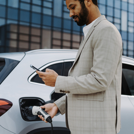 Man charging an electric vehicle (EV) while using his phone.
