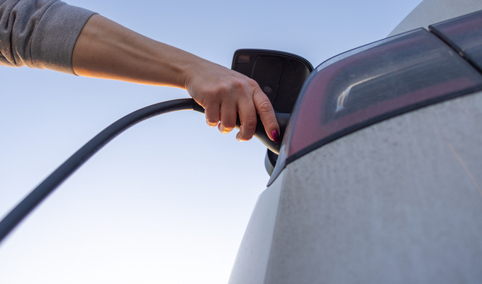 Person Charging Electric Car Against Clear Sky