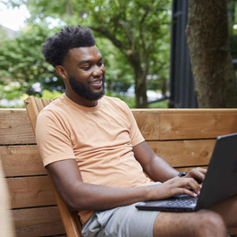 Photo of a young African American man, working from a remote location on his computer