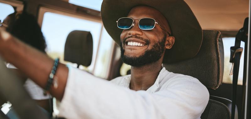 Smiling man wearing sunglasses driving on a summer vacation