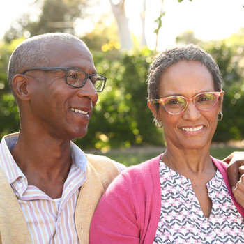 Black elderly couple sitting outside on a bench.
