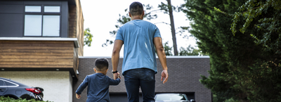 Father walking up driveway with son