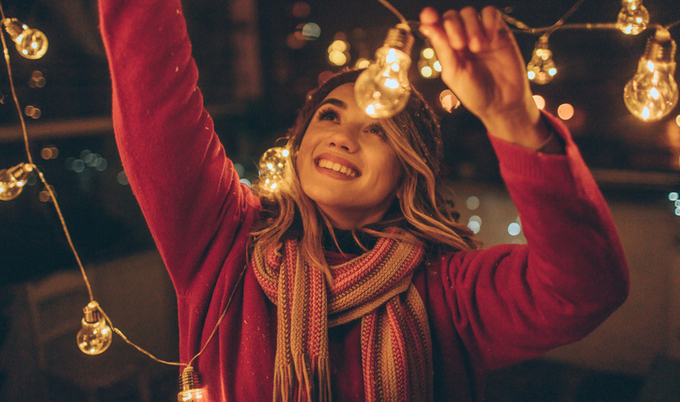 Woman putting up a sting of lights at night.