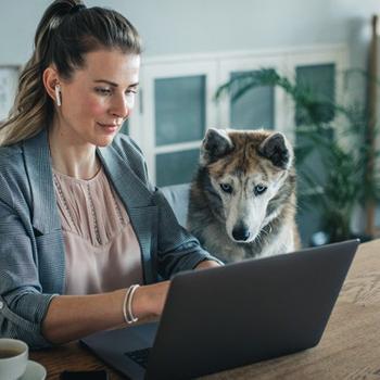 Woman sitting at table looking at tablet.