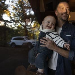 dad and baby looking outside of house smiling 