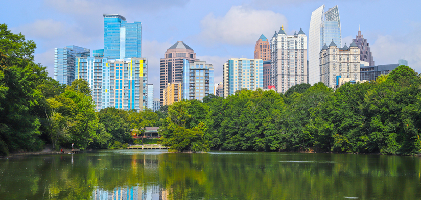 Atlanta buildings reflected, between trees and clouds. View from Piedmont Park.