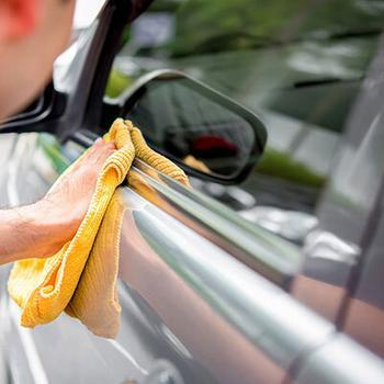 Man wiping car with a microfiber cloth.