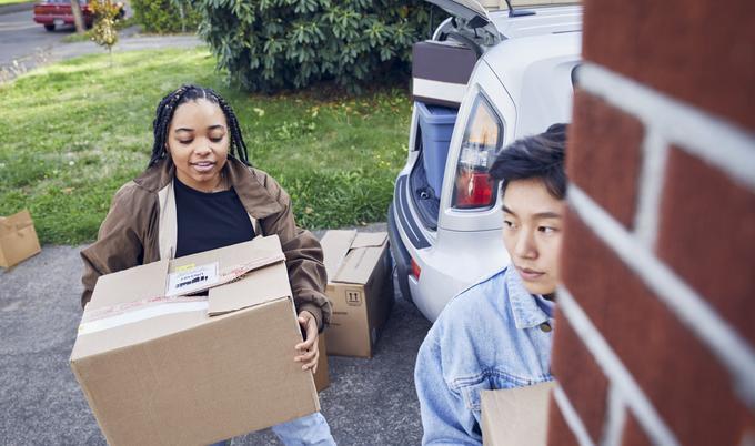 Woman and man moving boxes out of a SUV.