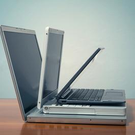 Side view of three old laptop piled up