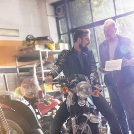 Mechanic and customer talking in motorcycle shop. 