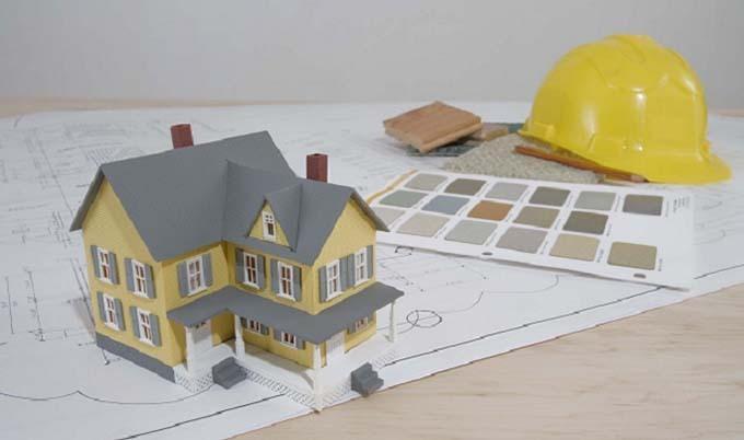 Model of house with blueprints and hard hat.