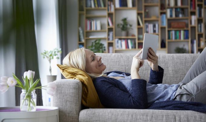 Woman lying on couch and using a tablet device.