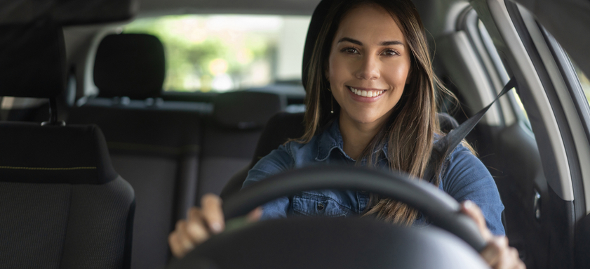 Portrait of a happy woman looking very happy driving a car and smiling.