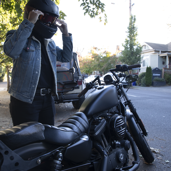 female getting ready to ride motorcycle putting helment on