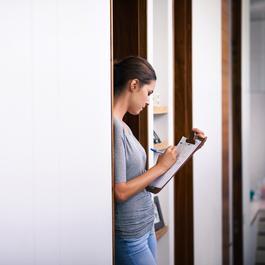 Woman writing on her clipboard in doorway